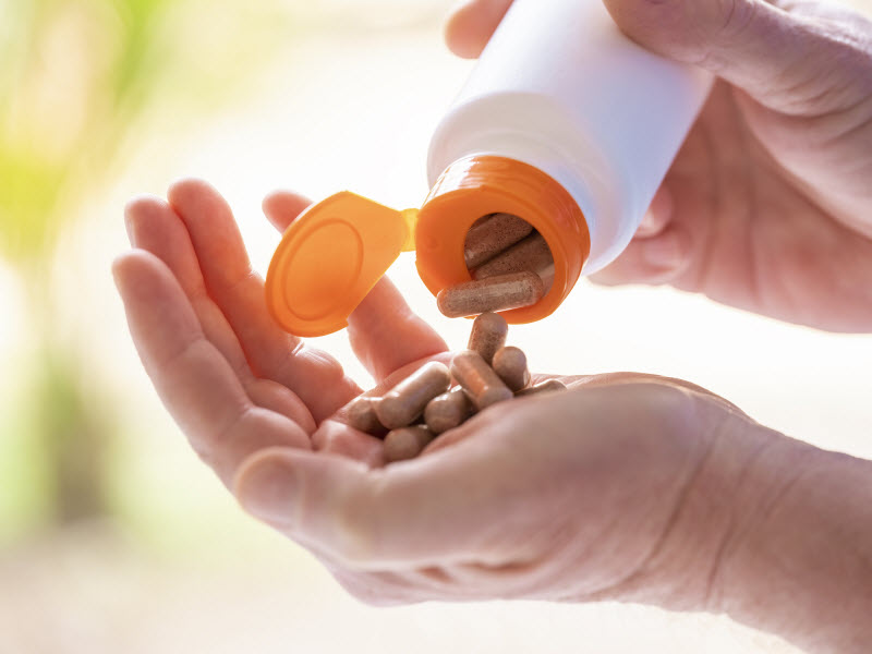 Herbs for Energy Pouring from Supplement Bottle into Open Palm of Woman | Vitacost.com/blog