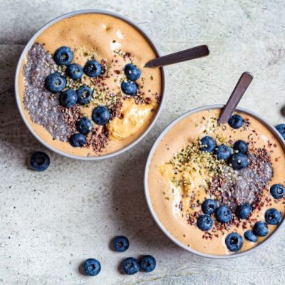 Two Chocolate Smoothie Bowls with Chia Seeds and Blueberries in Gray Bowls with Spoons on Marble Counter | Vitacost.com/blog