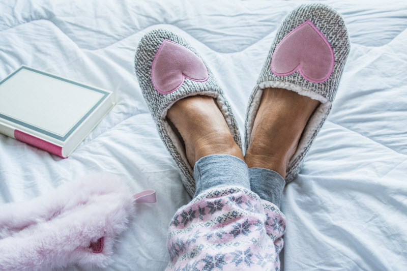 What is Sleep Hygiene Represented by View of Woman's Feet in Slippers in Bed | Vitacost.com/blog
