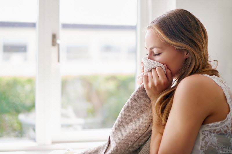 Side View of Woman Smelling Laundry Wondering if she has Fragrance Sensitivity | Vitacost Blog