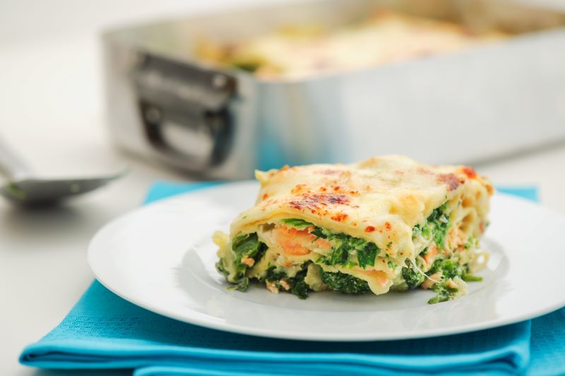 Slice of Dairy Free Lasagna with Spinach and Salmon on White Plate with Teal Napkin | Vitacost.com/blog