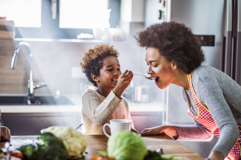 Mother Tasting Food Son Made in Kitchen to Represent Concept of Kids Eating Habits | Vitacost.com/blog
