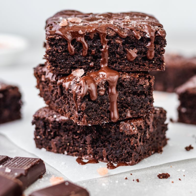 Stack of Sea Salt & Dark Chocolate Gluten Free Brownies on Parchment Paper | Vitacost. com/blog