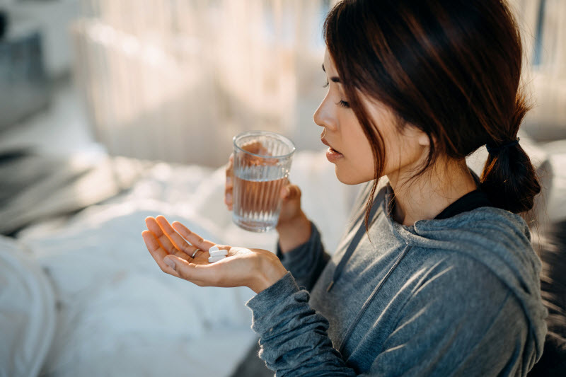 Woman Concerned About Vitamin Deficiency Symptoms Taking Supplements with Water | Vitacost.com/blog