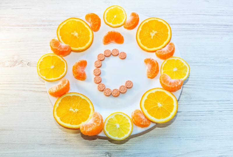 Plate With Orange Slices and Letter C Spelled in Supplement Tablets to Represent Concept What is Liposomal Vitamin C | Vitacost.com/blog