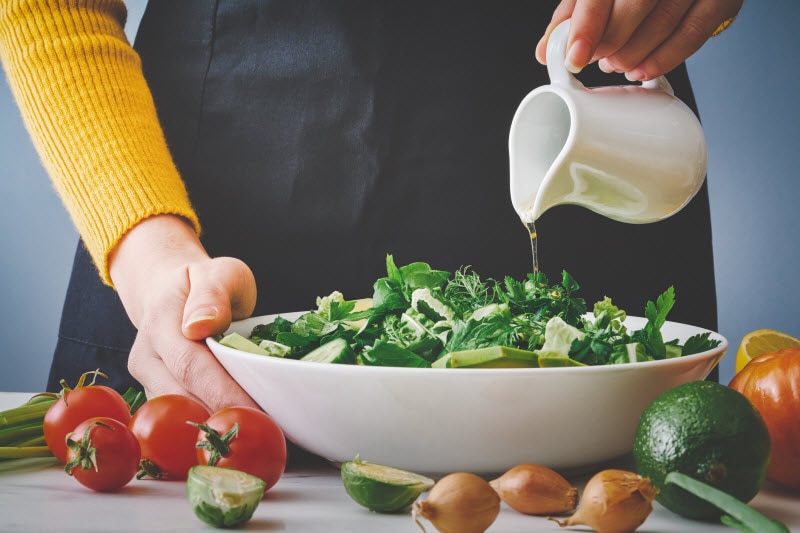 Torso View of Woman Pouring Heathy Salad Dressing Onto Colorful Salad | Vitacost.com/blog