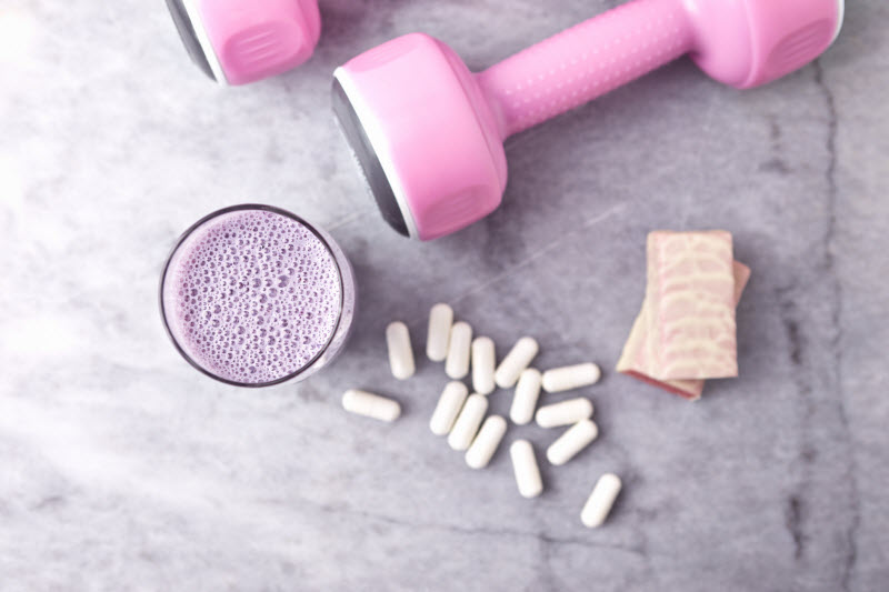 Benefits of BCAAs Represented by Smoothie, Capsules and Pink Weights on Marble Surface | Vitacost.com/blog