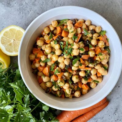 Curried Chickpea Salad Recipe in a White Bowl Surrounded by Lemon Halves, Parsley & Carrots | Vitacost.com/Blog