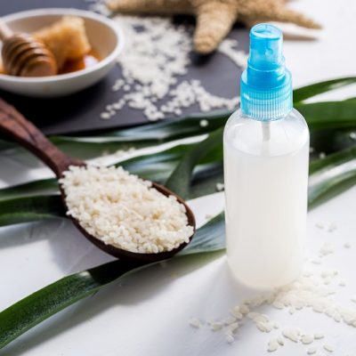 Homemade Rice Water Rinse for Hair in Spray Bottle Next to Spoon of Rice | Vitacost.com/Blog