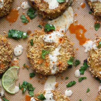 Fried Green Tomatoes on a Sheet Pan Drizzled in White Sauce and Garnished With Chopped Cilantro to Represent Baked Fried Green Tomatoes Recipe | Vitacost.com/Blog