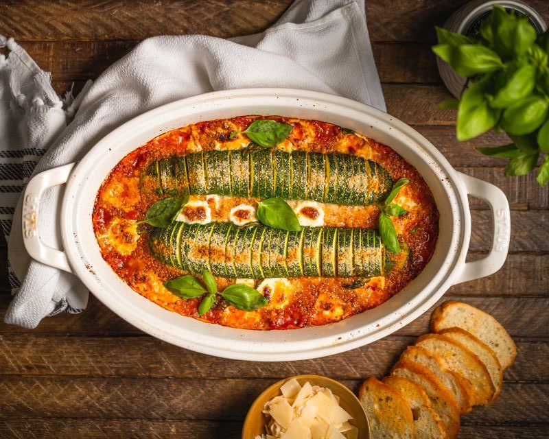 Baked Hasselback Zucchini Parmesan in White Baking Dish on Wood Table | Vitacost.com/blog