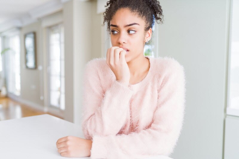 Nervous-Looking Woman in Kitchen Trying to Learn How to Stop Biting Your Nails | Vitacost.com/blog