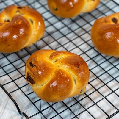 Round, Braided Challah Bread Loaves With Raisins Sit on a Cooling Rack to Represent Vegan Challah | Vitacost.com/Blog