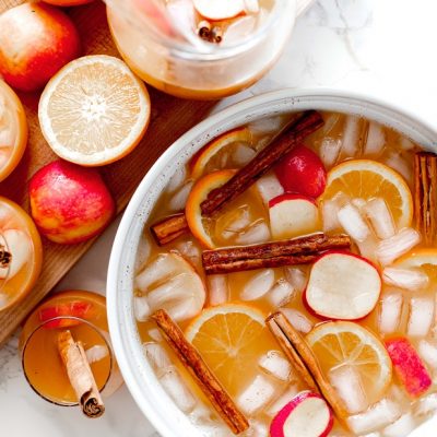 A Large White Bowl is Filled With Icy Punch With Orange Slices, Cinnamon Sticks and Apple Slices to Represent a Witches Brew Halloween Cocktail | Vitacost.com/Blog