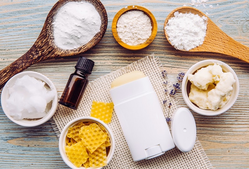 Homemade Deodorant in Tube Surrounded by Ingredients, Including Baking Soda, Arrowroot Powder, Coconut Oil and Essential Oil | Vitacost.com/Blog