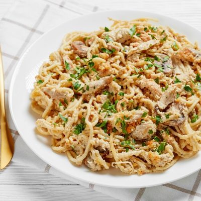 A White Plate With Creamy Pasta, Shredded Turkey and Fresh Herbs Represent Leftover Turkey Casserole | Vitacost.com/Blog