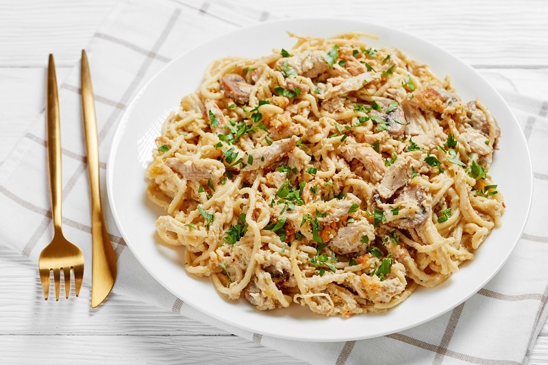 A White Plate With Creamy Pasta, Shredded Turkey and Fresh Herbs Represent Leftover Turkey Casserole | Vitacost.com/Blog
