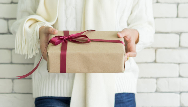 A Gift Guide for Immune Health: 2021 Holidays Woman Who Followed Gift Guide for Immune Health Holding Healthy Wrapped Gift with Red Ribbon | Vitacost.com/blog