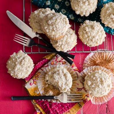 Several Streusel-Topped Muffins Sit on a Red Tablecloth to Represent Eggnog Muffin Recipe | Vitacost.com/Blog