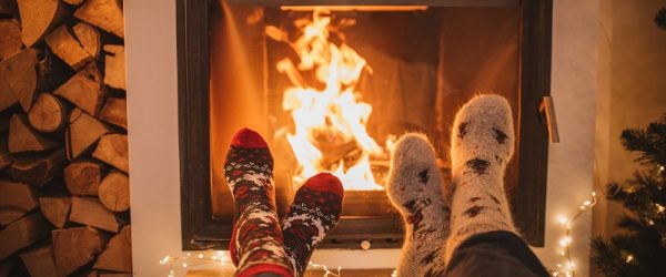 Two Pairs of Feet Covered in Cozy Holiday Socks Warm by a Fireplace to Represent a Campfire Starter | Vitacost.com/Blog