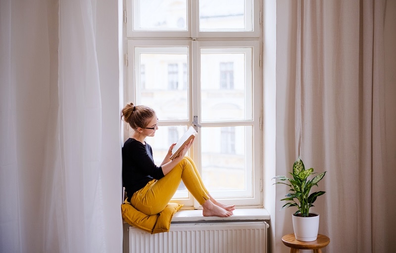 Woman on Window Seat Monotasking by Reading a Book | Vitacost.com/Blog