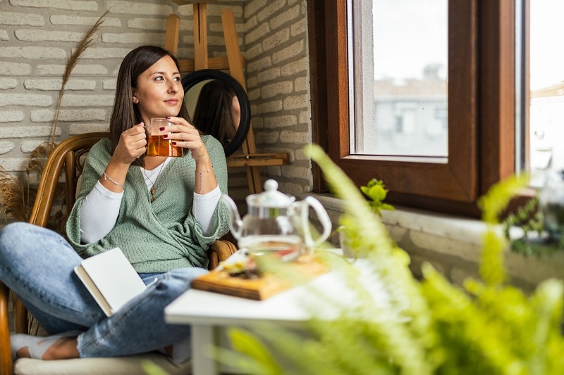A Young Woman Relaxes With a Cup of Tea and a Journal to Represent Morning Rituals | Vitacost.com/Blog