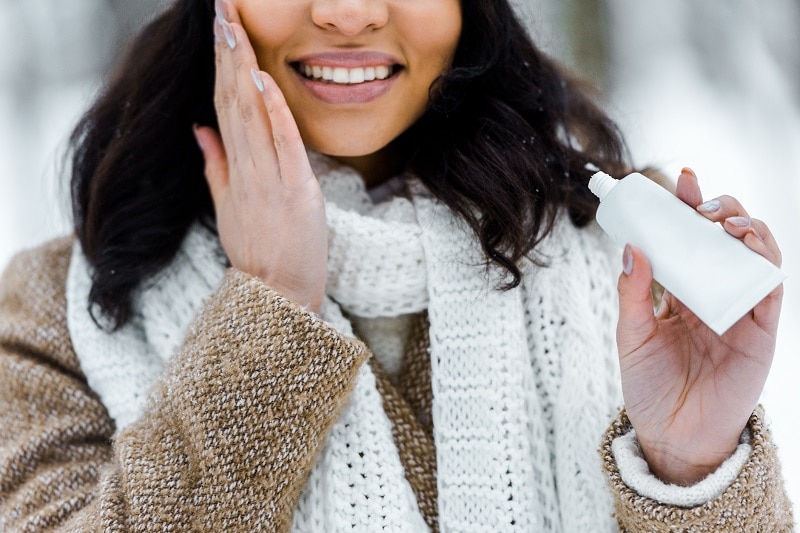 Woman Outside Applying Heavyweight Face Moisturizer in the Winter | Vitacost.com/Blog