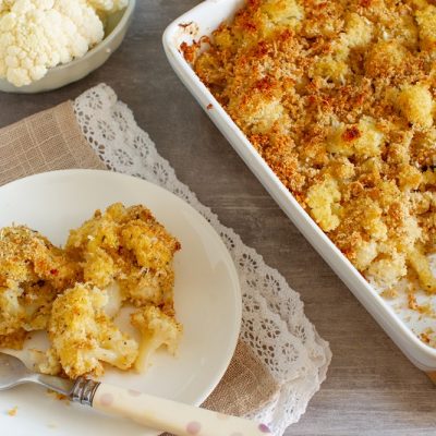 Roasted Cauliflower With Turmeric in a White Casserole Dish Sit Next to a White Plate With a Helping of Cauliflower | Vitacost.com/Blog