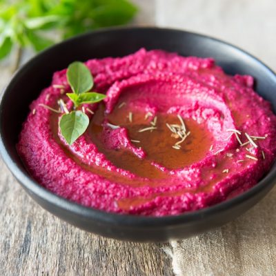 Homemade Roasted Garlic Beet Hummus in Bowl Garnished with Herbs | Vitacost.com/Blog