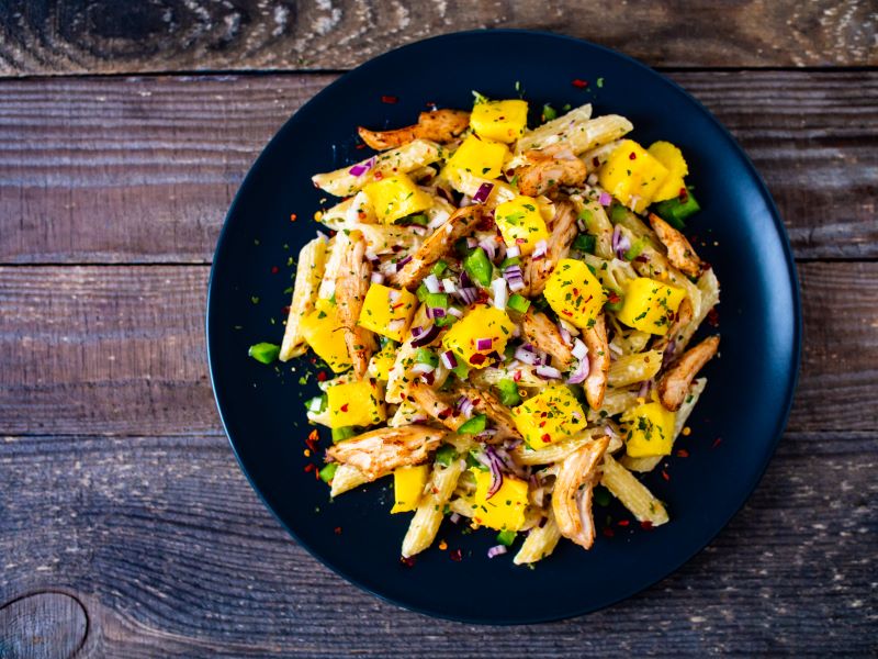 Plant-based ragu pasta made with jackfruit and mango on black plate atop wood table | Vitacost.com/blog