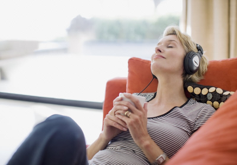 Woman With Headphones Lying on Couch to Represent Music and Mental Health Benefits | Vitacost.com/blog