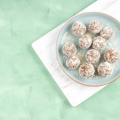 A Light Blue Plate of Protein Balls Coated in Coconut Flakes Sits on a White Board to Represent a Protein Balls Recipe | Vitacost.com/Blog