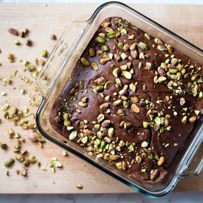 Mint & Pistachio Gluten Free Brownies in Baking Dish Surrounded by Pistachios on Wooden Cutting Board | Vitacost.com/blog