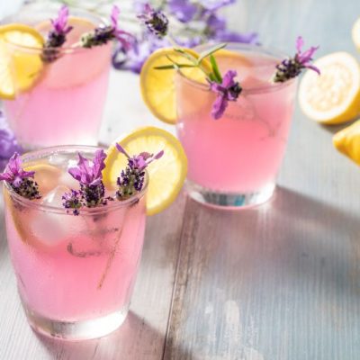 Lavender Lemonade in Glasses on Glossy Counter Surrounded by Lavender Flowers and Lemons | Vitacost.com/blog
