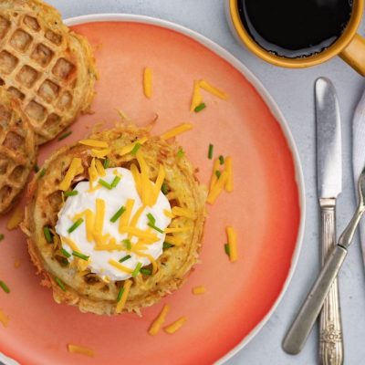 An Overhead View of an Orange Plate With Circle Potato Waffles Topped with Sour Cream, Chives and Shredded Cheddar | Vitacost.com/Blog