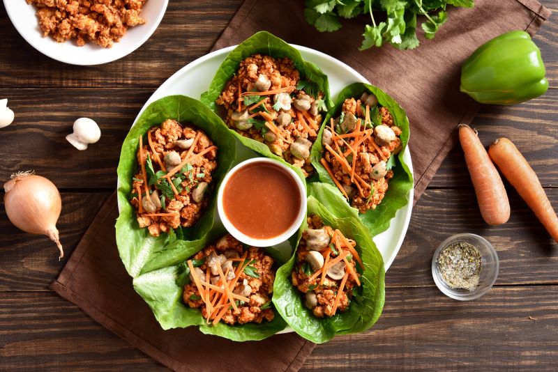 Chicken Lettuce Wraps on Serving Plate With Sauce Bowl in Center on Wood Tabletop | Vitacost.com/blog
