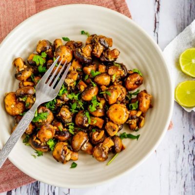 Stir-Fried Mushrooms on White Round Plate on White Wooden Table With Linen Napkin and Lemon Slices | Vitacost.com/blog