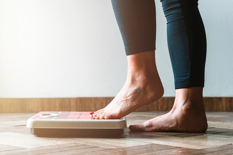 5 Signs of Unhealthy Weight Loss Practices Woman Stepping on Scale | Vitacost.com/Blog