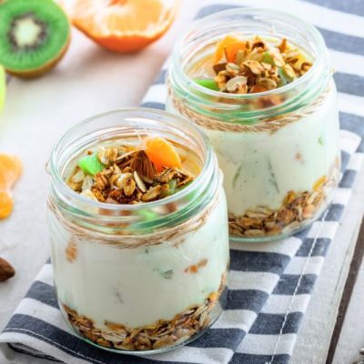 High Protein Yogurt Cup with Granola & Fruit in Rustic Glass Jar on Striped Napkin on Whitewashed Table | Vitacost.com/blog