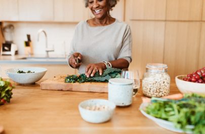Woman Cutting Kale in Kitchen Following Tips for Reversing Prediabetes | Vitacost.com/blog