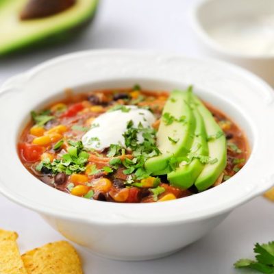 Chicken Enchilada Soup With Avocado, Sour Cream and Cilantro in Soup Bowl