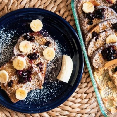 Baked French Toast with Bananas, Blueberries and Powdered Sugar on Navy Blue Plate