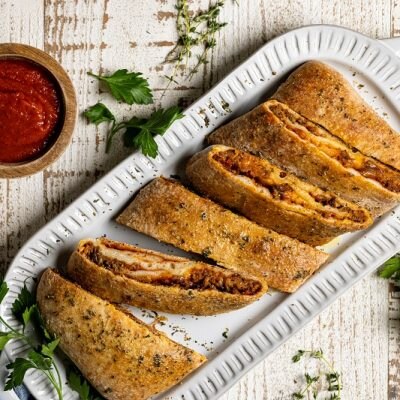 Homemade Stromboli with Gluten-Free Pizza Crust on Platter with Sauce on the Side