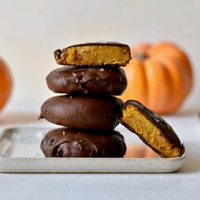 Chocolate-Dipped Vegan Pumpkin Cookies on Serving Plate on a Table in Front of Pumpkins