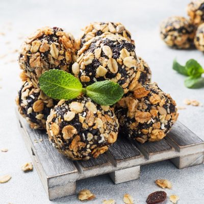 Chocolate Oat Dessert Balls Placed Together On A Decorative Pallet Surrounded By Oats In the Background.