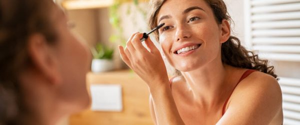 Smiling Woman Using Vegan Makeup Applying Mascara in Mirror