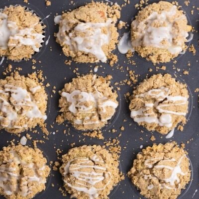 A Muffin Pan is Filled With Gluten-Free Apple Muffins Topped With Streusel and Vanilla Glaze.
