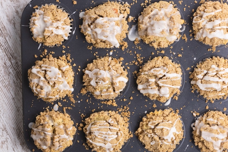 A Muffin Pan is Filled With Gluten-Free Apple Muffins Topped With Streusel and Vanilla Glaze.