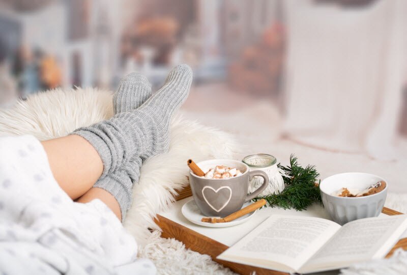 Woman Coping with Holiday Stress Relaxing With Fuzzy Blanket and Cup of Hot Cocoa