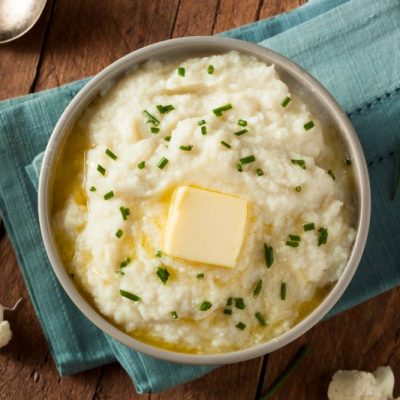 Garlic Mashed Cauliflower Recipe in Bowl on Kitchen Towel Set on Rustic Wooden Table